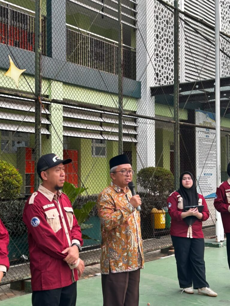 Dewan Pembina OSIS SMA Islam Al Azhar 22 Cikarang sedang memberikan sambutan menggunakan mikrofon di lapangan sekolah.